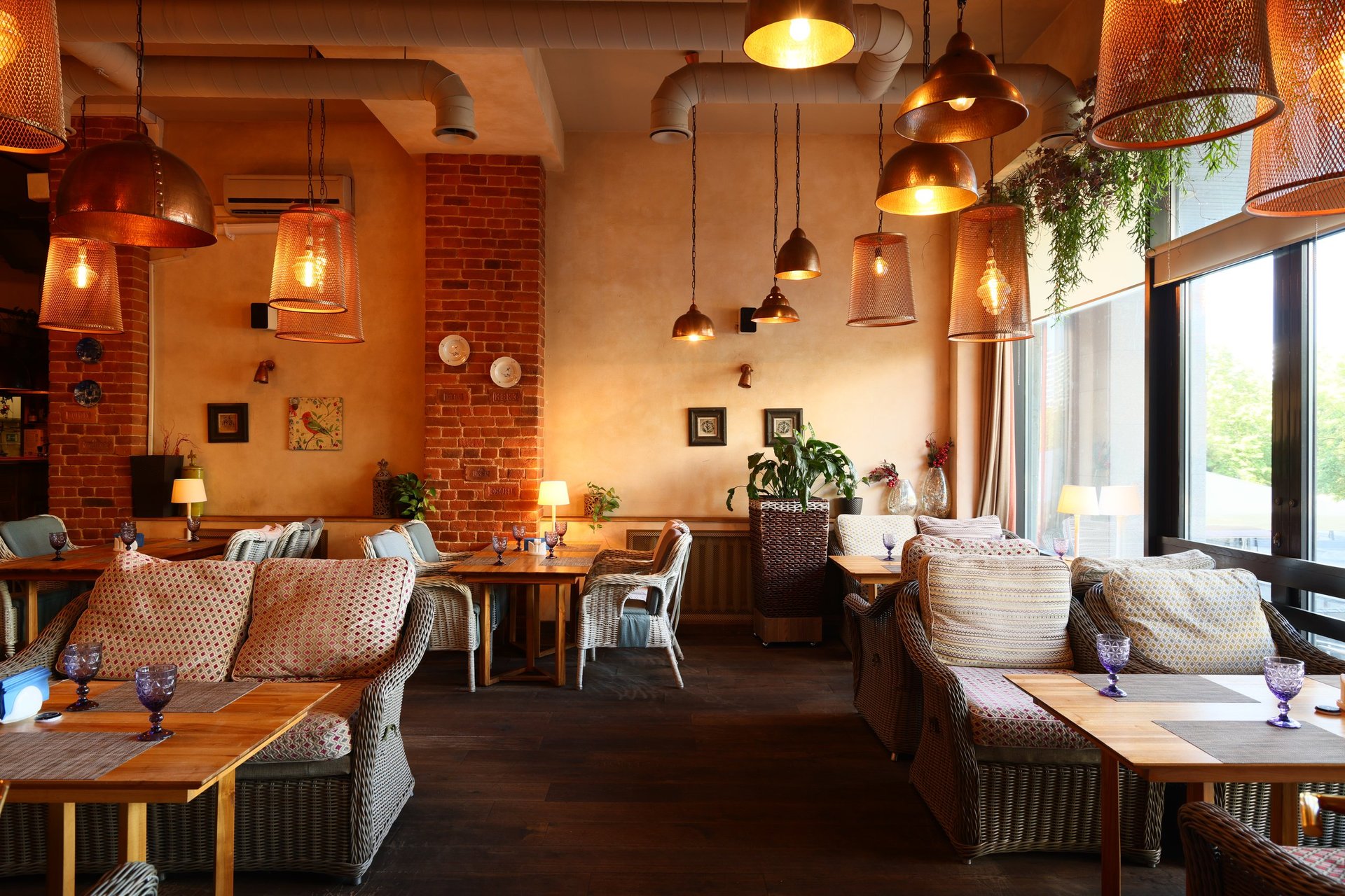 Warm community café interior with sofas, tables, pendant lights, and plants